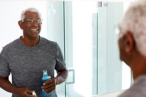 Man smiling at reflection while holding mouthwash