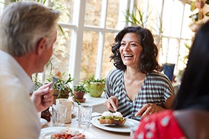 Woman smiling while eating at restaurant with friends