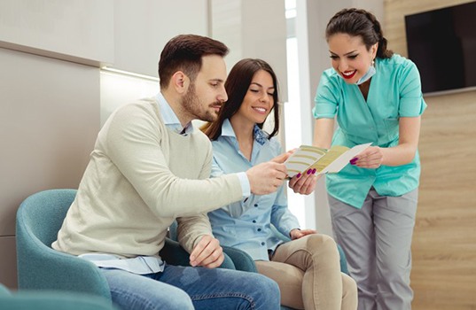 Dental hygienist shows couple brochure